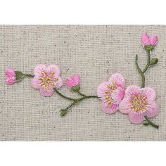 some pink flowers are on a beige cloth background with green stems and yellow center pieces