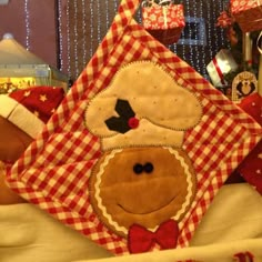 a teddy bear wearing a red and white checkered blanket with a christmas decoration on it