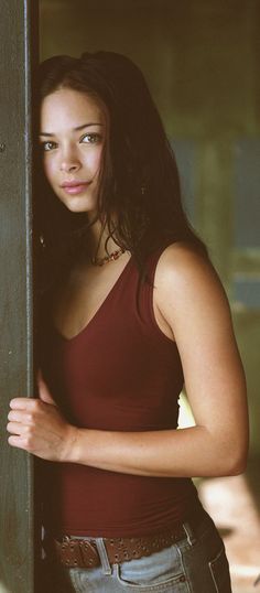 a beautiful young woman leaning against a wall