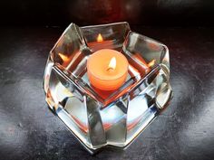 a lit candle in a glass bowl on a table