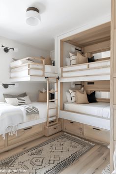 there are bunk beds in the room with white sheets and pillows on top of them