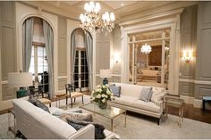 a living room with couches, chairs and chandelier in it's center