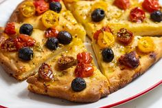 a pizza with olives and tomatoes on a plate