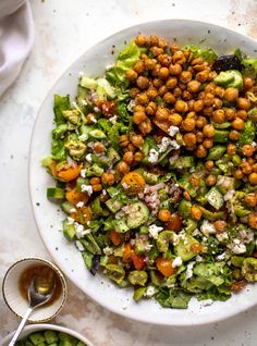 a salad with chickpeas and lettuce in a white bowl on a table