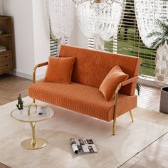 a living room with an orange couch, coffee table and chandelier hanging from the ceiling