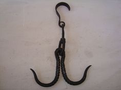 an old hook is hanging on the wall with it's long black handle and looped ends