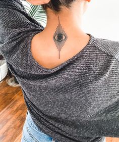 the back of a woman's neck with a sun tattoo on her left shoulder