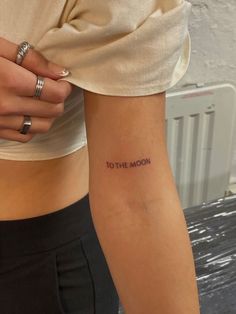 a woman's arm with the words to the moon tattooed on her left side