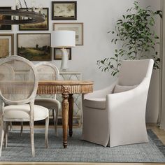 a dining room table with chairs and pictures on the wall above it, next to a white chair