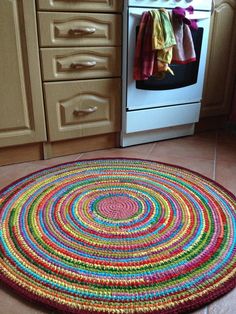 a multicolored rug in the middle of a kitchen floor next to an oven