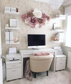 a white desk with a computer on top of it next to a wall mounted flower