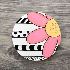 a painted flower sitting on top of a wooden table covered in black and white stripes