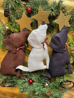 three stuffed animals sitting in front of a christmas tree with gold stars on their heads