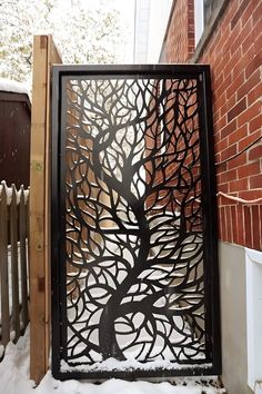 a metal tree is shown on the side of a building with snow in front of it