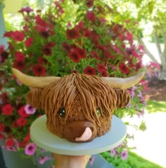 a cow head on top of a cake with flowers in the backgroung