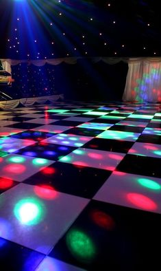 a dance floor with colorful lights on it and a piano in the background at night