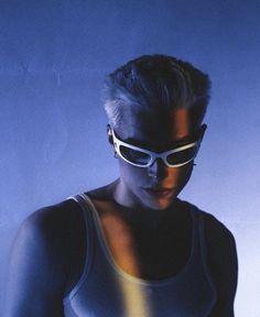 a woman wearing sunglasses and looking at her cell phone in front of a blue background