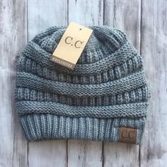 a blue knitted beanie with a tag on it sitting on a wooden surface