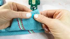 two hands are sewing on a blue towel