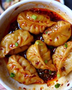 a bowl filled with dumplings covered in sauce