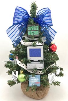 a computer christmas tree has been decorated with blue ribbon and ornaments, including an ornament that says computer whisperer