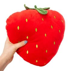 a hand holding up a red strawberry pillow