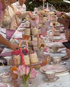 a group of people sitting at a table with plates and cups filled with cake on it