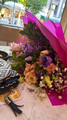 a bouquet of flowers sitting on top of a table next to a purse and scissors