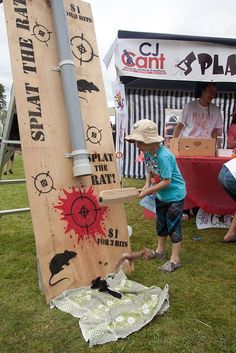 two young boys are playing with a wooden sign at an outdoor event in the grass