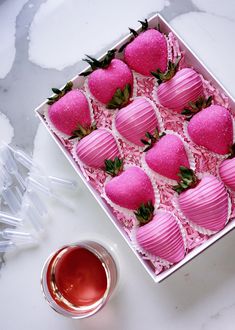 a box filled with pink chocolate covered strawberries next to a cup of tea and spoon