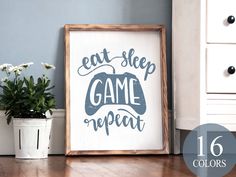 a sign that says eat sleep game repeat next to a potted plant on the floor