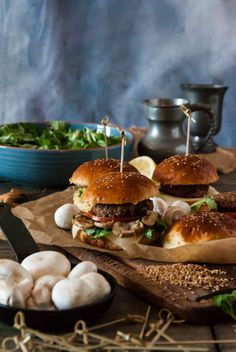 two burgers with toothpicks stuck in them sitting on top of a cutting board