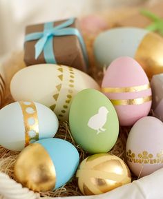 a basket filled with lots of different colored eggs next to some gold and white decorations