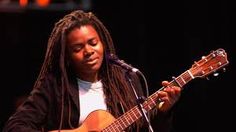 a woman with dreadlocks playing an acoustic guitar