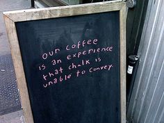 a chalkboard with writing on it sitting next to a metal container and trash can