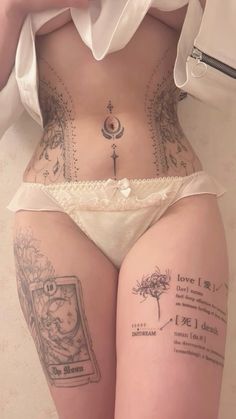 a woman with tattoos on her stomach is wearing a white panties and holding a cell phone