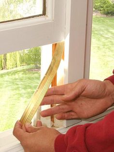 a person is opening the window with a pair of scissors in their hand, and they are working on trimming