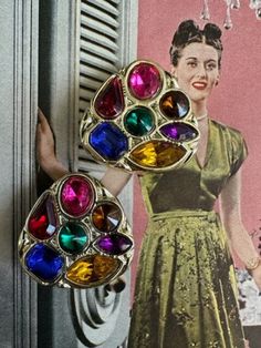 "80s Large Jewel Tone Gold Earrings. These earrings are so reminiscent of the 80s. They are a rounded corner triangular shape with seven jewel tone rhinestones . The colored stones are gold, purple, hot pink, green, red, blue , yellow. They measure 1 3/8\" in length and 1 3/8\" in width.  The earrings are lightweight since the base of the earrings are plastic. They are clip ons an the clips function well. Free Shipping in the U.S. when Purchasing $35 or more. Complementary Vintage Gift Wrap on t Jewel Tone Earrings, Vintage Jeweled Multicolor Earrings, 80's Earrings Vintage, Retro Multicolor Clip-on Earrings, 1980s Earrings