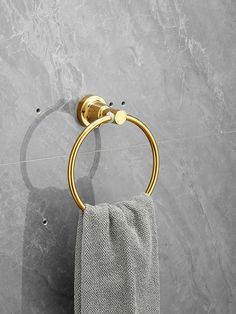 a gold towel ring on the wall next to a gray marble bathroom counter with grey tiles