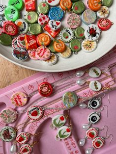 a white bowl filled with lots of different colored buttons on top of a pink tray