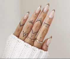 a woman's hand with tattoos on her fingers and fingernails in the shape of arrows