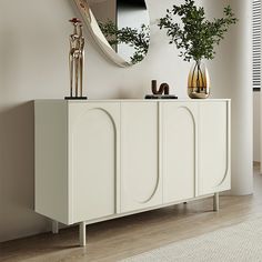 a white sideboard with two vases and a mirror