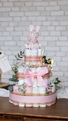 a baby shower cake with pink and white decorations on it's tiered stand