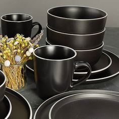 a table topped with black plates and cups