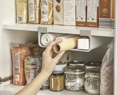 a person is opening the door to a pantry filled with spices and cereals on shelves