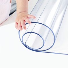 a baby's hand is on the edge of a sheet of clear plastic with blue lines