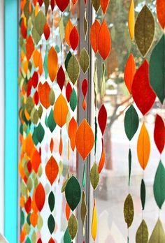 a close up of a window with colorful paper leaves hanging from it's side