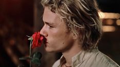 a man with long hair and a rose in his mouth