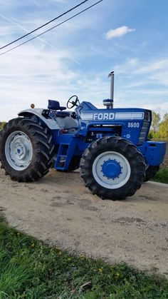 a blue tractor parked on top of a dirt road