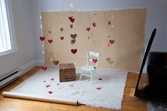 a white chair sitting on top of a rug next to a wall with hearts hanging from it